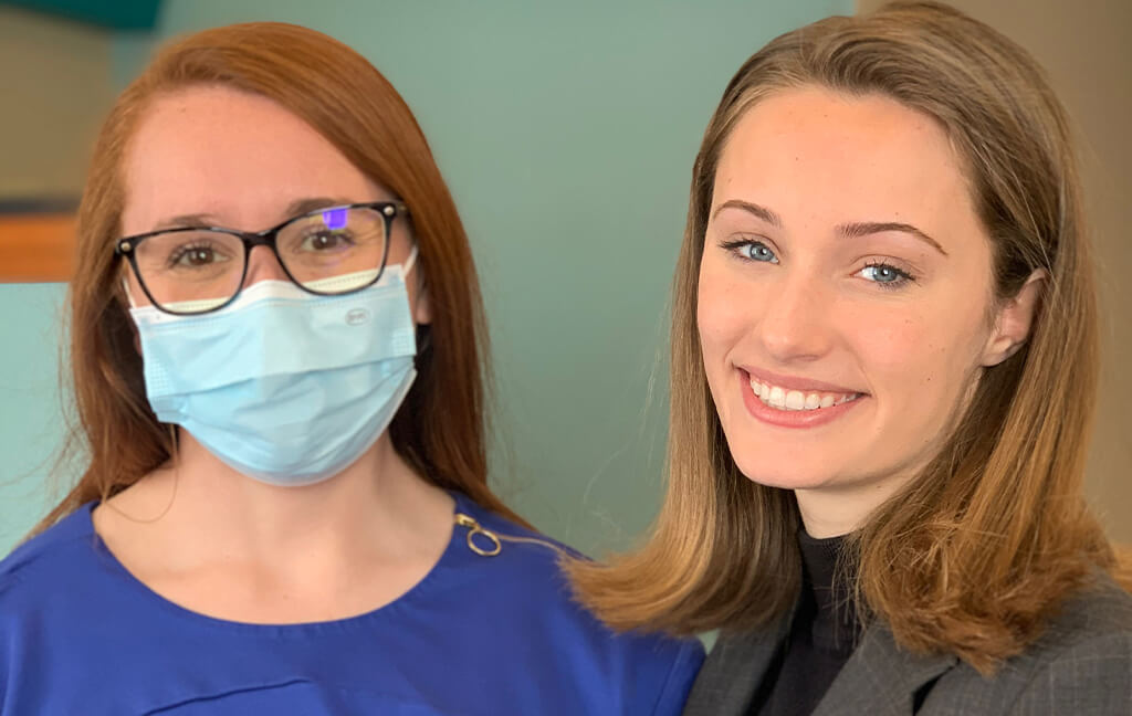 Two women smiling one with mask on